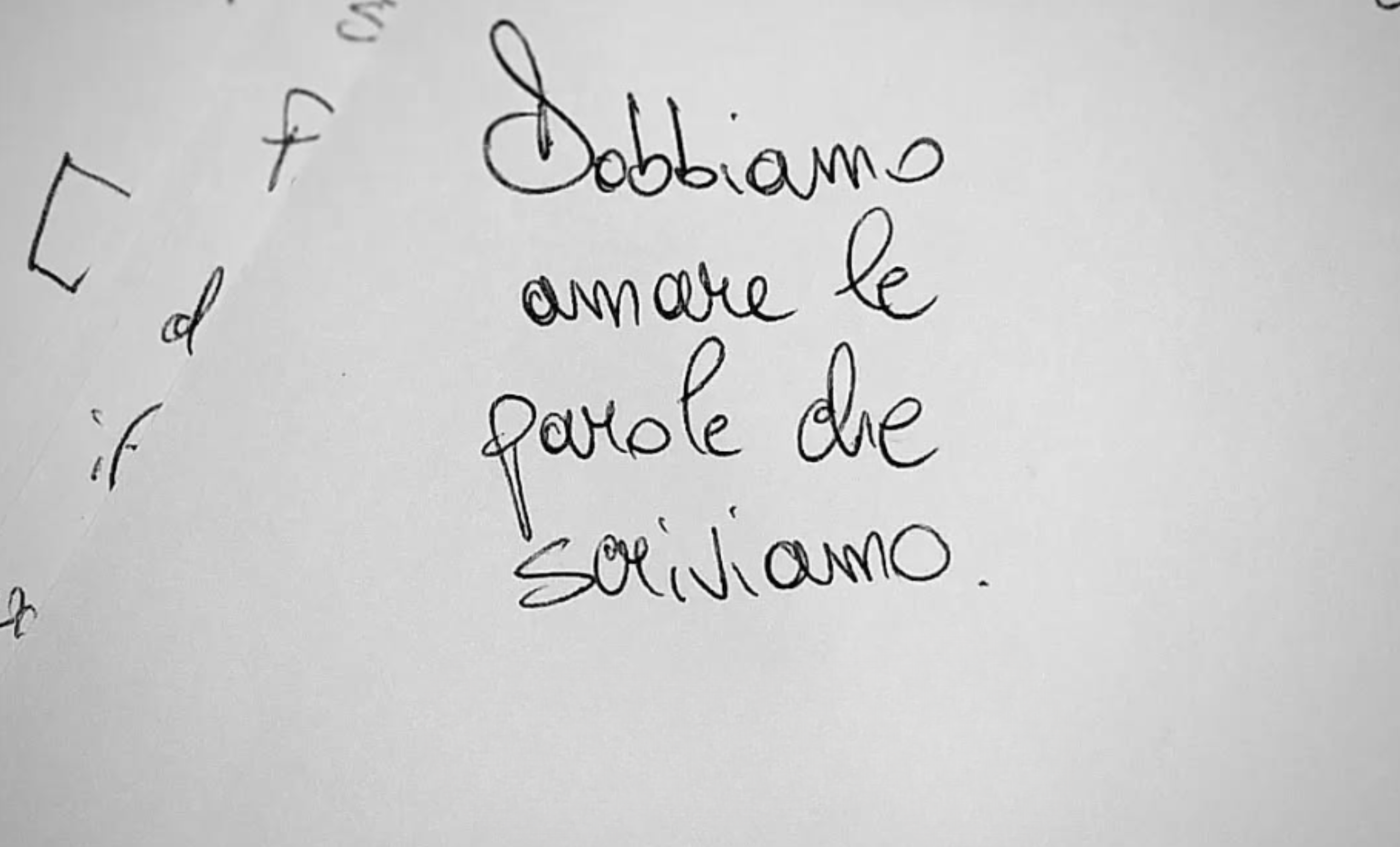 Un foglio bianco con scritto sopra, a mano, "dobbiamo amare le parole che scriviamo"
