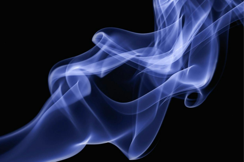 Una scrivania in legno con appoggiate sopra lettere, cartoline, appunti e un vasetto di fiori bianchi